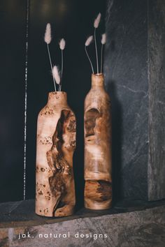 two wooden vases sitting next to each other on a shelf with feathers sticking out of them