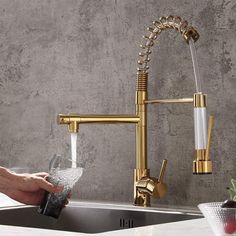 a person pouring water into a glass under a faucet in a kitchen sink