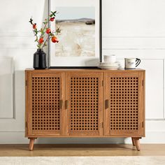 a wooden cabinet with two vases on top of it next to a framed photograph