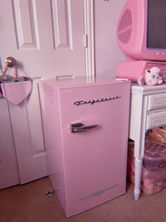 a pink refrigerator sitting next to a white dresser in a child's play room