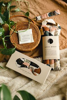 an assortment of items on a bed next to a basket with leaves and paper tags