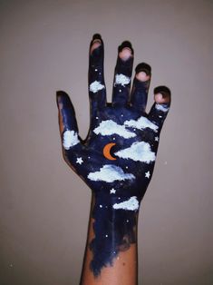 a person's hand painted with clouds and the moon