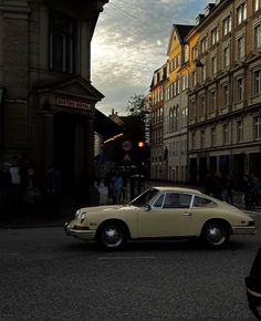 an old car is parked on the side of the road in front of some buildings