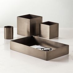 three square metal containers on a white table