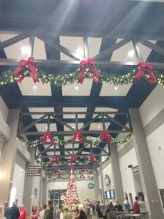 people are sitting at tables with christmas decorations on the ceiling