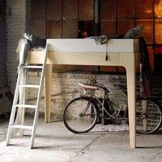 a bicycle is parked under a desk with a ladder