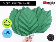 the paper leaf template is being held by a hand