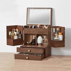 an open wooden box containing cosmetics and personal care items on a table with a mirror above it