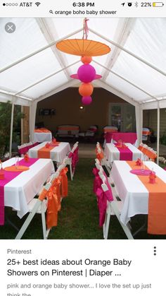 an outdoor tent with tables and chairs covered in pink and orange tablecloths, hanging from the ceiling