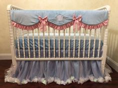 a white crib with blue bedding and pink ruffles on the bottom