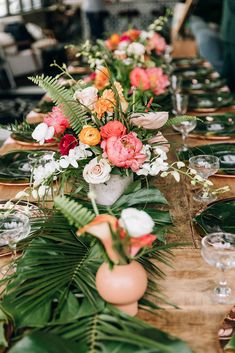 a long table is set with flowers and greenery for an elegant dinner or party