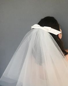 a woman wearing a white veil with a bow on it's head and back