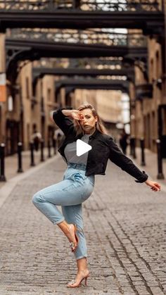 a woman standing on one leg in the middle of an alleyway with her arms stretched out