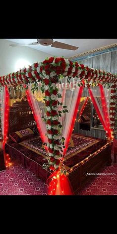 a decorated bed with red and white flowers on the headboard, along with lights