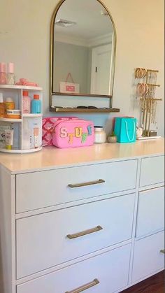 a white dresser topped with lots of drawers next to a mirror and shelf filled with personal care items