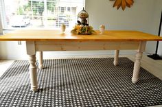 a wooden table sitting on top of a black and white checkered rug next to a window