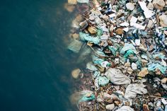 an aerial view of a river filled with garbage and rocks, next to a body of water