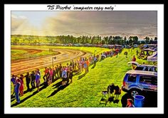 a group of people standing on top of a grass covered field next to a race track