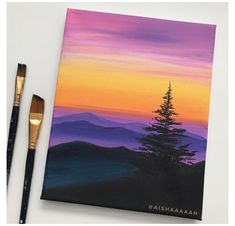 an acrylic painting of a pine tree in the mountains at sunset with paintbrushes next to it