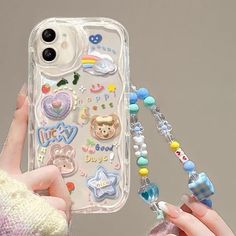 a person holding up a phone case with various stickers and beads on the back