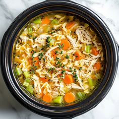 a bowl of chicken noodle soup with carrots, celery and parsley