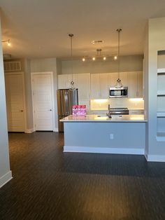 an empty kitchen with white cabinets and wood flooring is seen in this image from the living room