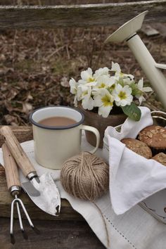 a cup of coffee sitting on top of a wooden table next to some crochet hooks