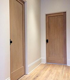 an empty room with two wooden doors and hard wood flooring on the other side