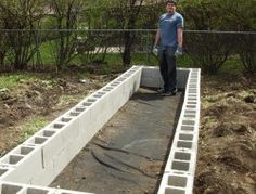 a man standing on top of a cement slab in the middle of a garden area