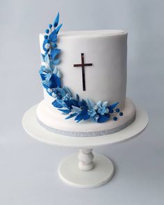 a white cake with blue flowers and a cross on top