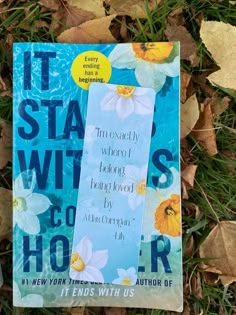 a book laying on top of leaves in the grass with it's cover pulled back