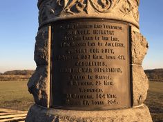 a monument in the middle of a field with a plaque on it's side