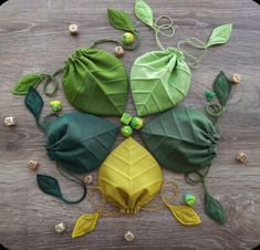 four green and yellow leaves are arranged on a wooden surface, with beads in the middle