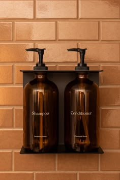 two brown soap dispensers sitting on top of a shelf next to a brick wall