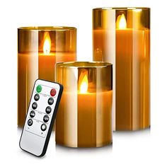 three lit candles with remote controls in front of them