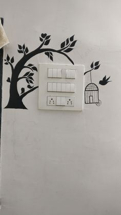 a white light switch sitting next to a tree with a birdcage on it