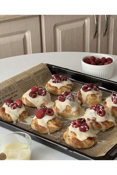 small pastries are sitting on a baking tray with strawberries in the middle and milk next to them