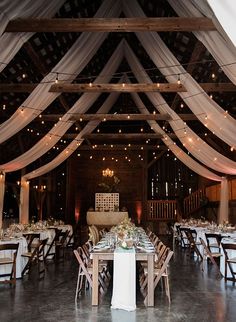 the inside of a barn with tables and chairs set up for a formal dinner or reception