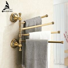 two towels hanging on the side of a wall next to a towel rack with gold fixtures