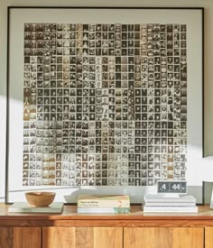 a wooden dresser topped with books next to a wall mounted art piece on top of it