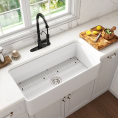 a white kitchen sink sitting under a window next to a cutting board with lemons on it