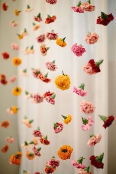 an arrangement of flowers floating in the air on curtains with white drapes behind them