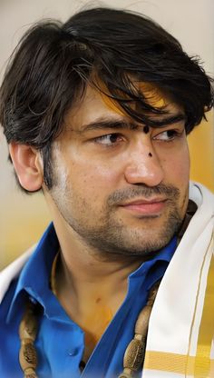 a close up of a person wearing a blue shirt and white scarf with gold stripes