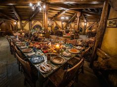 a large dining table set up in the middle of a room with wooden walls and beams