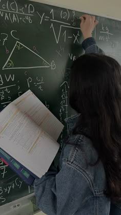 a woman writing on a blackboard with chalk