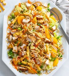 a white plate topped with salad next to a fork and knife on top of a table