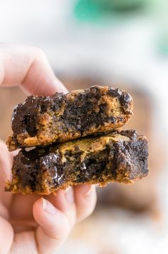 two chocolate chip cookies are being held by someone