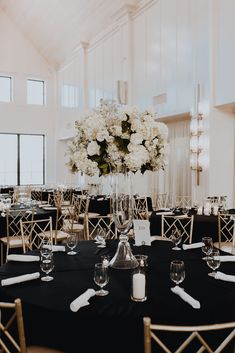 an elegant centerpiece with white flowers sits on top of a black linen covered table