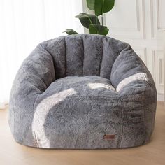 a grey bean bag chair sitting on top of a wooden floor next to a potted plant