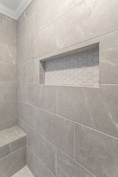 a white tiled bathroom with gray walls and floor tiles on the shower wall, along with an open window